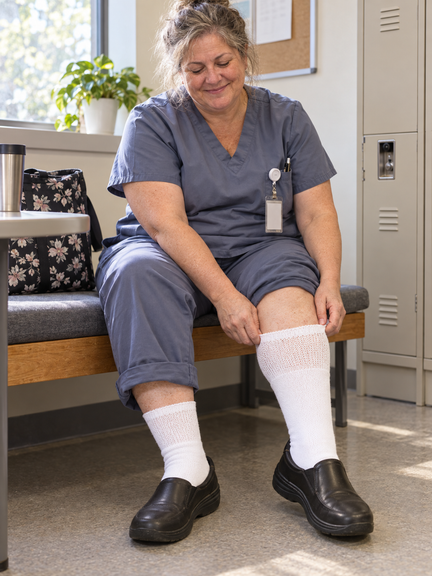 Nurse seated at the end of a shift, wearing wide-calf Diabetic Sock Club socks